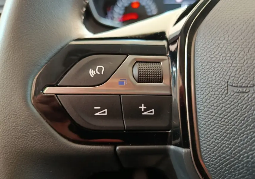 Gros plan sur les commandes multifonctions noires du volant cuir du Peugeot 208 blanc, version 2023 PureTech 75 S&S Style.