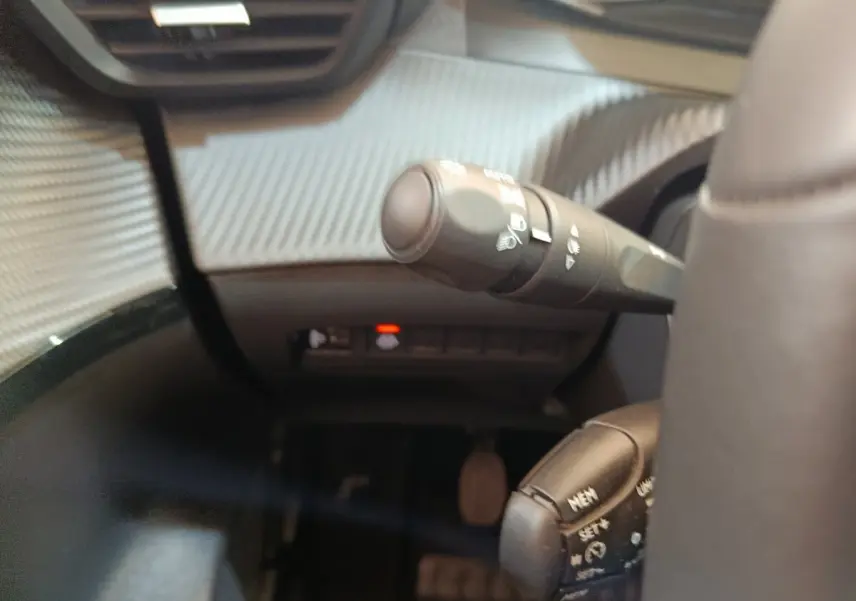 Détail intérieur du combiné de commandes au volant cuir d’une Peugeot 208 blanche, version PureTech 75 S&S Style 2023.