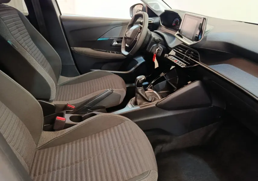 Intérieur de la Peugeot 208 PureTech 75 S&S Style 2023, vue côté conducteur, sièges tissu gris et tableau de bord moderne.