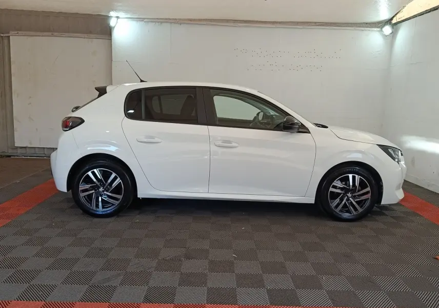 Profil droit d'une Peugeot 208 blanche 2023, avec jantes alliage noires et rétroviseurs ton caisse.