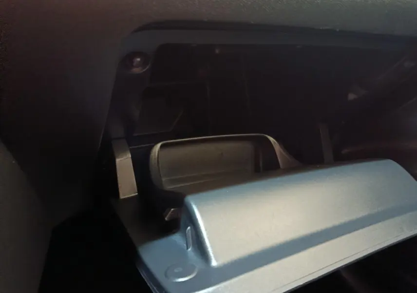 Gros plan sur le compartiment à gants ouvert de la Peugeot 208 PureTech 75 S&S Style, intérieur noir.