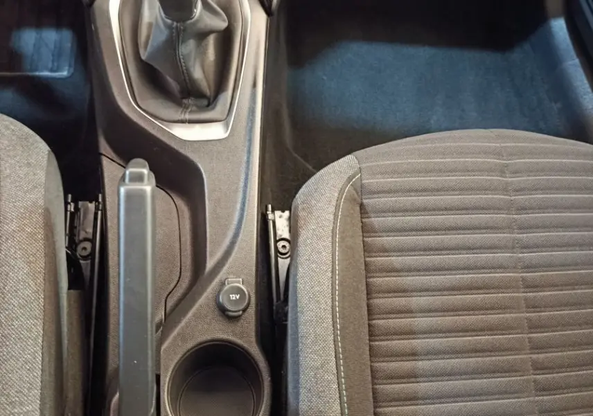 Vue plongeante sur la console centrale intérieure de la Peugeot 208 blanche, avec levier de vitesse manuel et siège tissu gris.