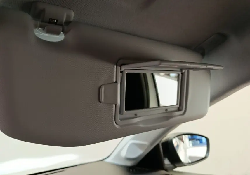 Miroir de courtoisie ouvert sur pare-soleil gris clair côté conducteur dans l’habitacle d’une Peugeot 208 blanche.