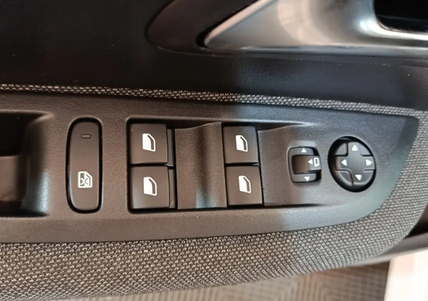 Détail des commandes des vitres et réglages des rétroviseurs sur la porte côté conducteur d’une Peugeot 208 blanche.