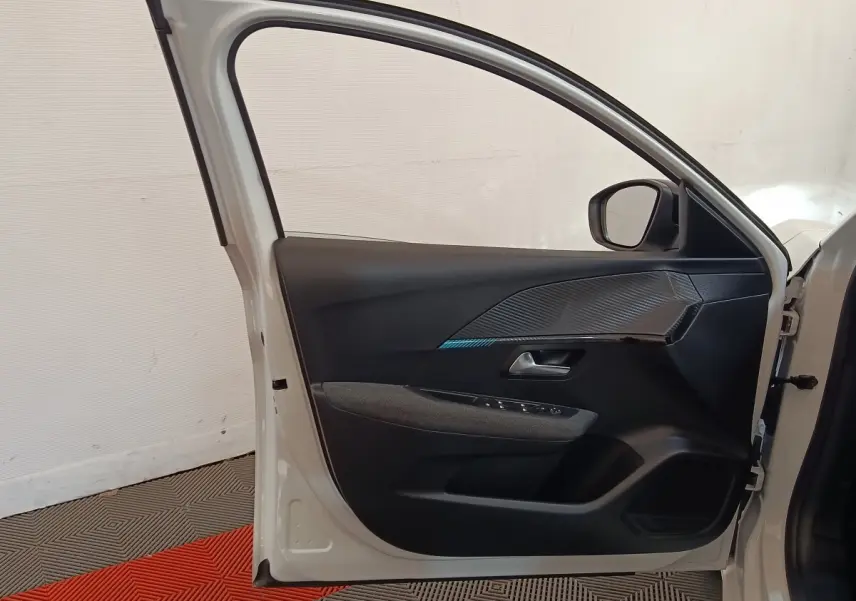 Vue intérieure de la porte avant gauche blanche d'une Peugeot 208 2023, avec garniture noire et détails texturés.