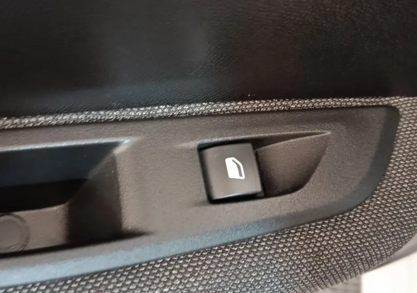 Gros plan sur le bouton de commande de lève-vitre électrique côté conducteur de la Peugeot 208 blanche 2023.