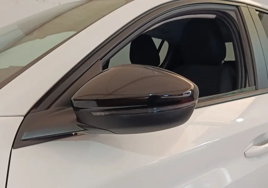 Rétroviseur noir brillant côté conducteur d'une Peugeot 208 blanche PureTech 75 S&S Style 2023, vue latérale rapprochée.