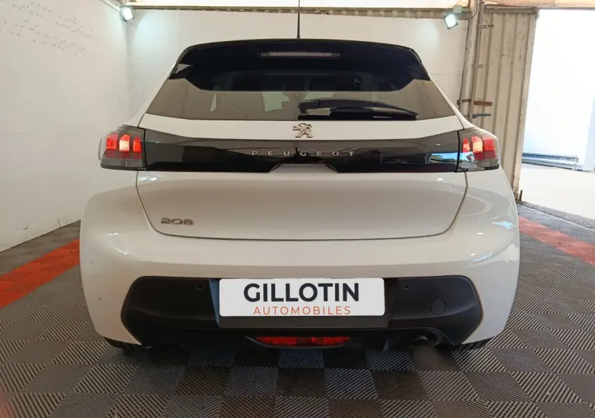 Vue arrière d'une Peugeot 208 blanche 2023 avec feux LED et bande noire distinctive sur le hayon.