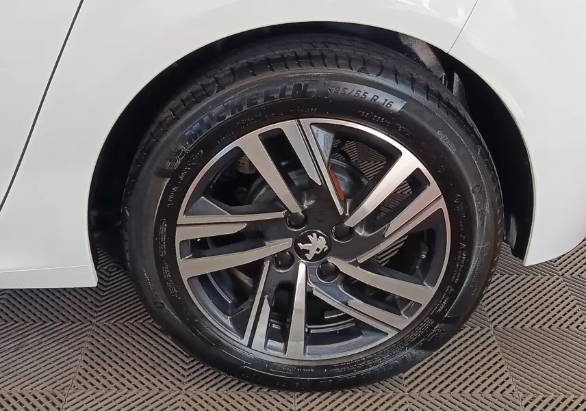Gros plan sur la roue arrière droite blanche d'une Peugeot 208 PureTech 75 S&S Style avec jante alliage noire et argent.