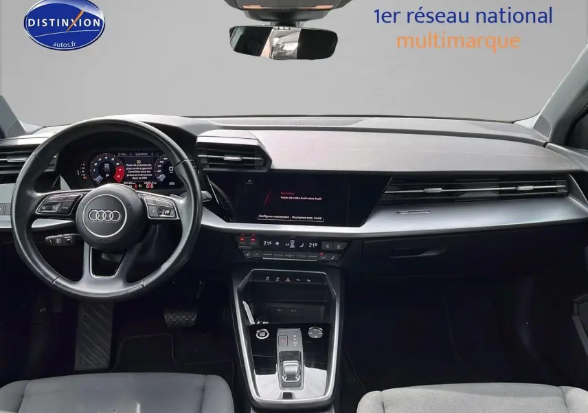 Intérieur de l'Audi A3 Sportback 2023 vu de face, tableau de bord moderne avec écran digital et volant cuir multifonction.