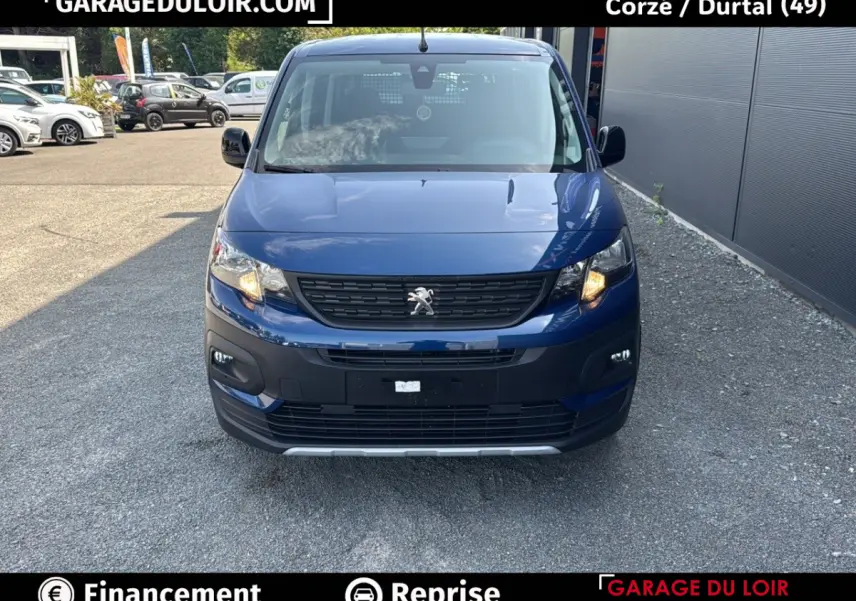 Vue avant d'un Peugeot Rifter 1.5 BlueHDi 100 bleu, avec calandre noire et feux allumés, sur parking extérieur.