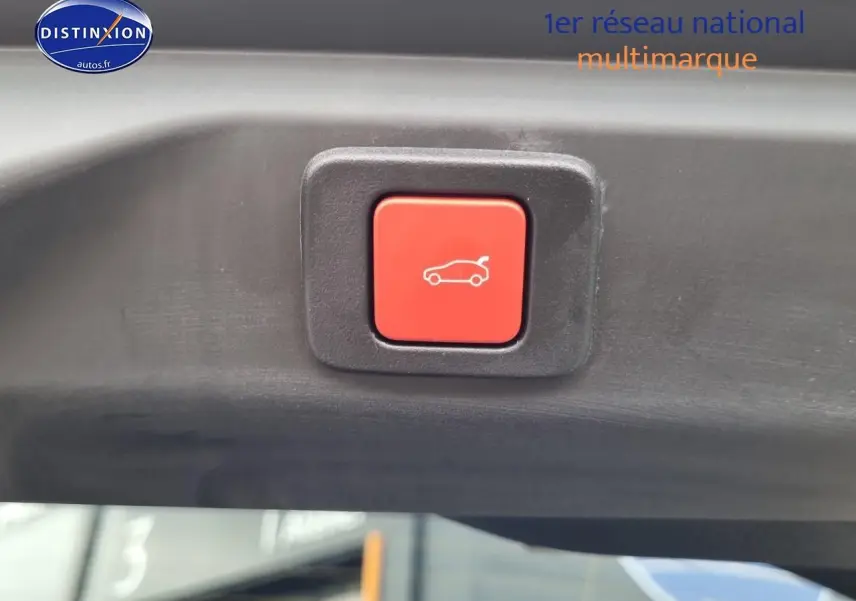 Bouton rouge d'ouverture électrique du coffre visible sur le hayon intérieur d'un Peugeot 3008 blanc.