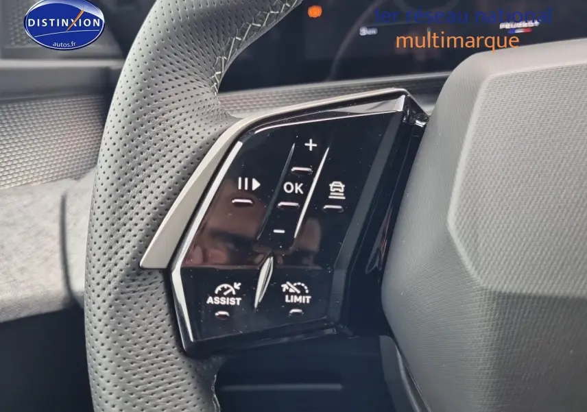 Gros plan sur les commandes noires du volant cuir perforé côté gauche du Peugeot 3008 blanc hybride 2025.