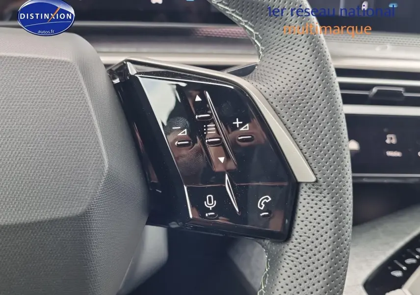 Gros plan sur les commandes vocales et audio du volant cuir perforé d'un Peugeot 3008 blanc, version hybride 2025.