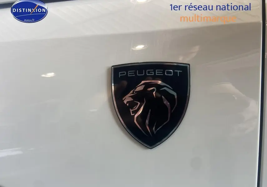 Gros plan sur le logo Peugeot noir et argent sur la carrosserie blanche brillante du SUV 3008 hybride.