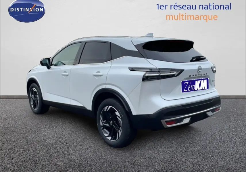 Vue 3/4 arrière droite d'un Nissan Qashqai blanc nacré métal 2025 avec jantes noires et toit noir contrasté.