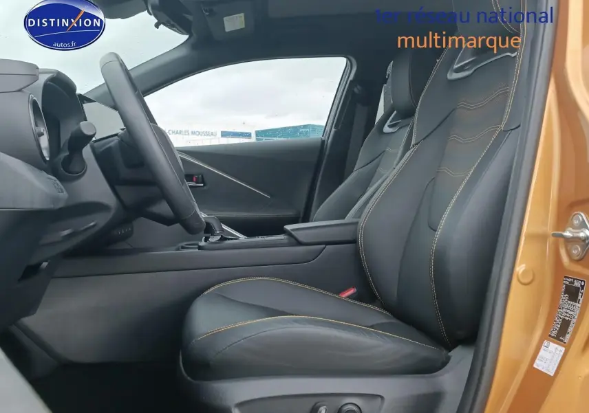 Vue intérieure côté conducteur du Toyota C-HR hybride 2025 or/noir, avec sièges sport noirs et surpiqûres jaunes.