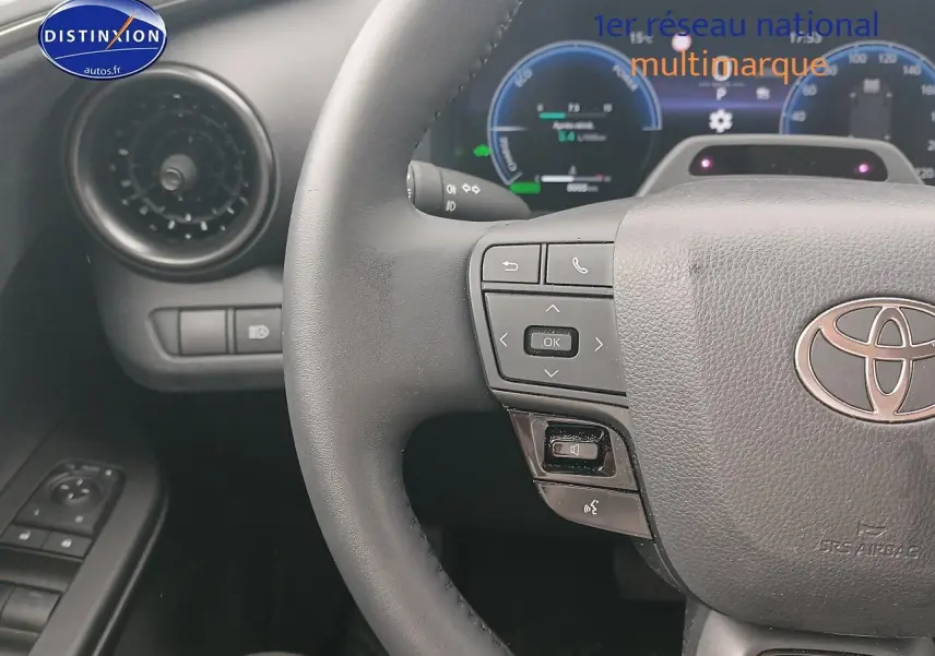 Vue rapprochée du volant multifonction noir et du tableau de bord digital du Toyota C-HR hybride 2025 or/noir.