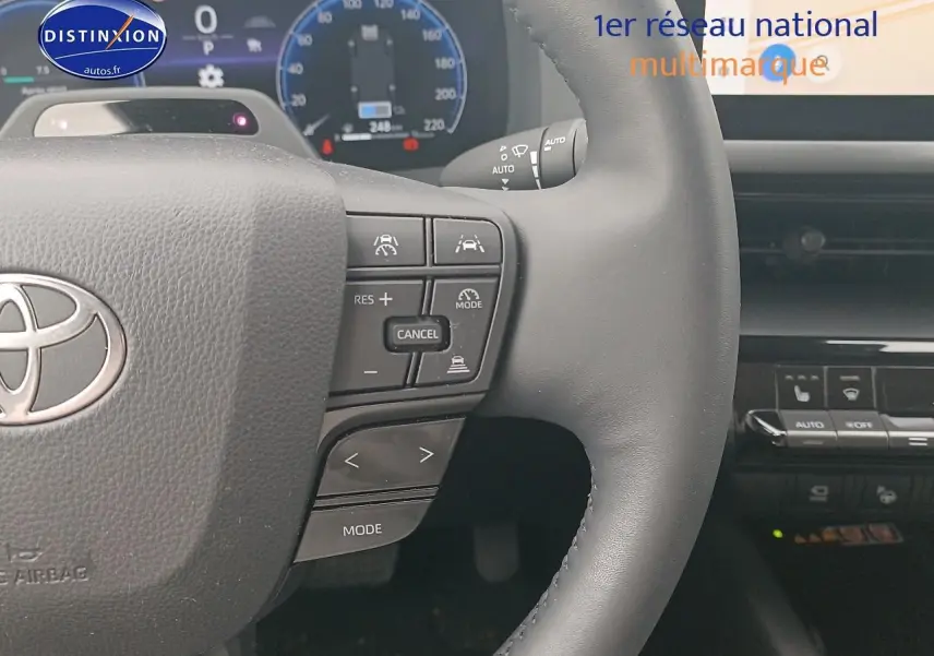 Gros plan sur le volant multifonction noir du Toyota C-HR hybride 2025 avec commandes de régulateur et affichage numérique.