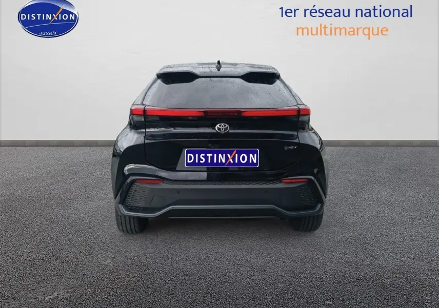 Vue arrière d'un Toyota C-HR hybride 2025 noir avec feux arrière LED en bandeau et toit panoramique visible.