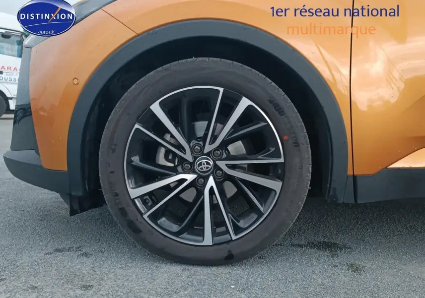 Gros plan sur la roue avant gauche du Toyota C-HR or et noir, avec jante alu bicolore et logo Toyota central.