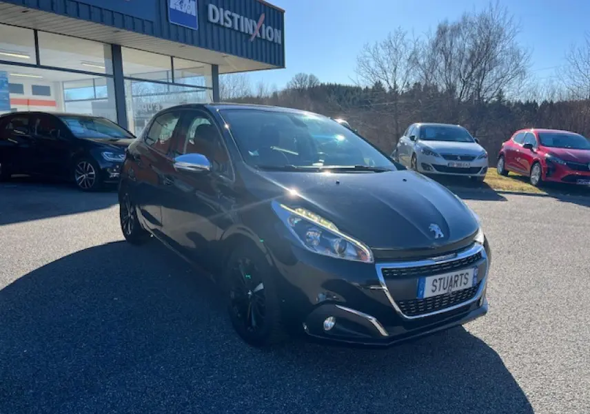 Peugeot 208 noire vue en 3/4 avant droit, avec jantes noires et calandre chromée brillante.