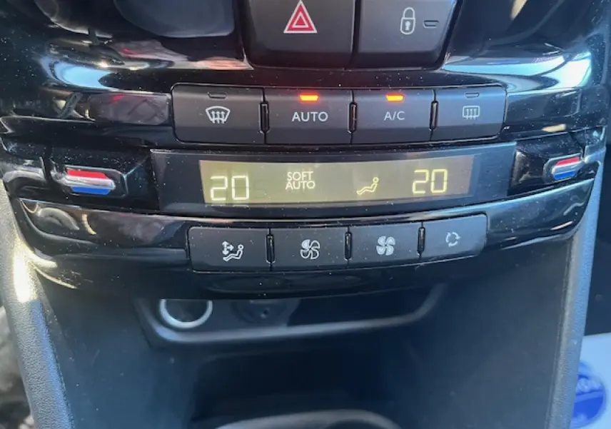 Gros plan sur la console centrale de la Peugeot 208 noire, affichant la climatisation automatique réglée à 20°C.