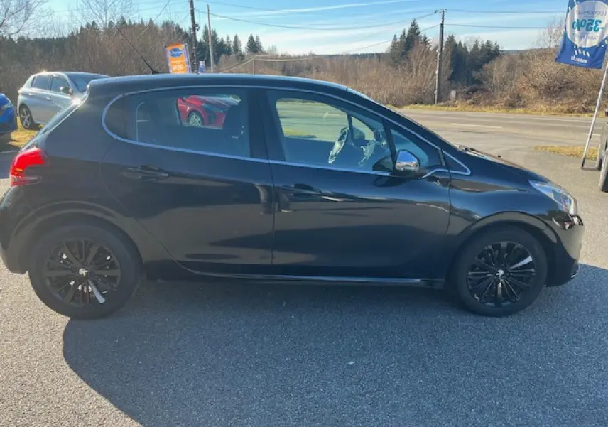 Profil côté gauche d'une Peugeot 208 noire de 2017 avec jantes noires et rétroviseurs chromés, stationnée en extérieur.
