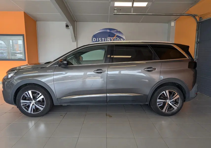 Profil côté gauche d'un Peugeot 5008 gris 2020 GT Line en intérieur, avec jantes alliage et vitres teintées.