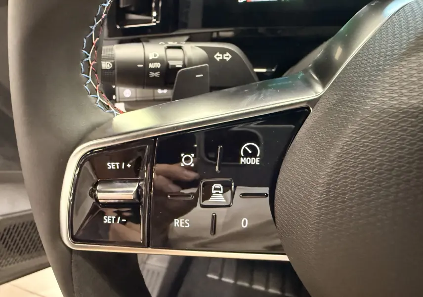 Gros plan sur les commandes de régulateur de vitesse au volant du Renault Austral blanc nacré, finition Esprit Alpine.
