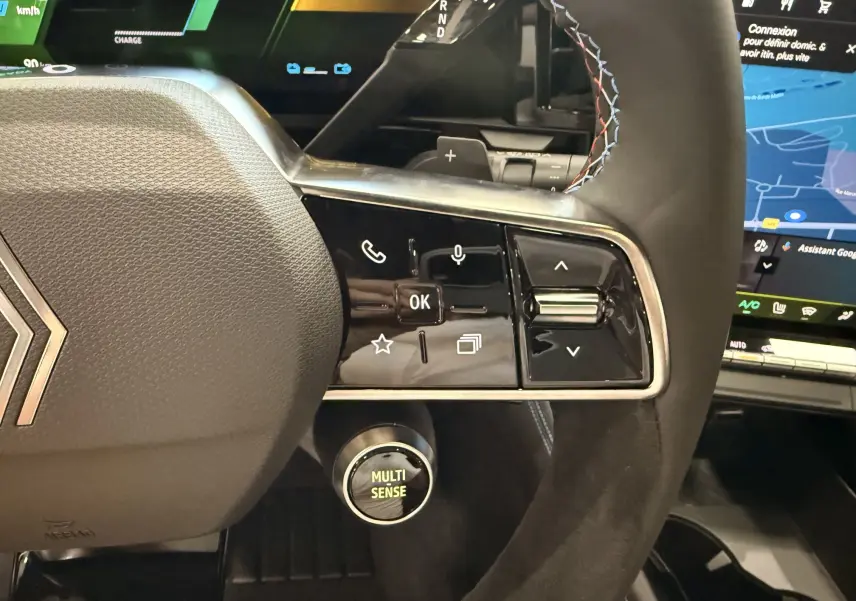 Gros plan sur le volant du Renault Austral blanc nacré, montrant les commandes multifonctions et le bouton Multi Sense.