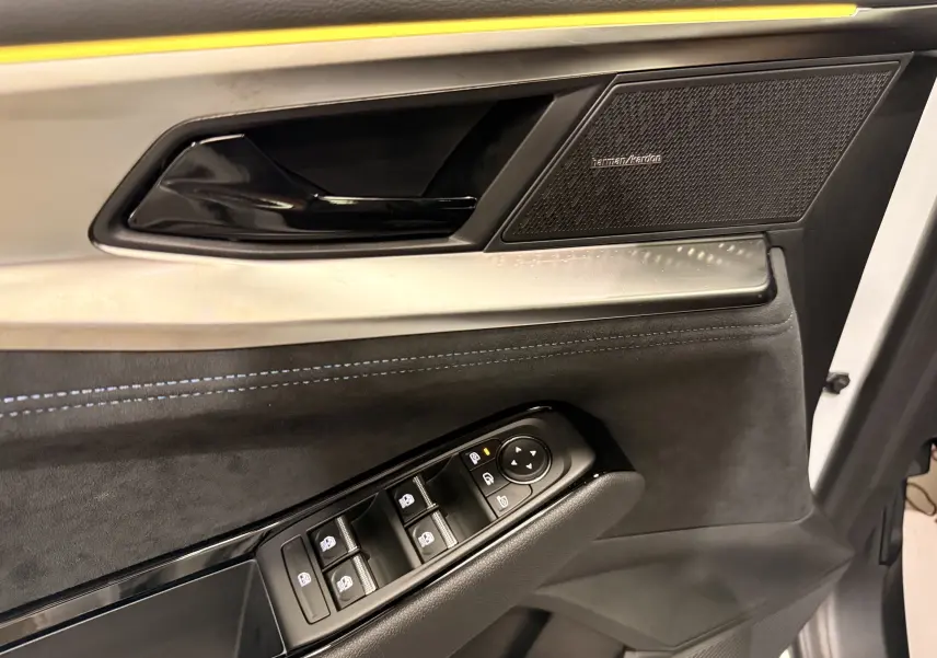 Gros plan sur la porte intérieure côté conducteur du Renault Austral blanc nacré, avec commandes de vitres et haut-parleur Harman/Kardon.