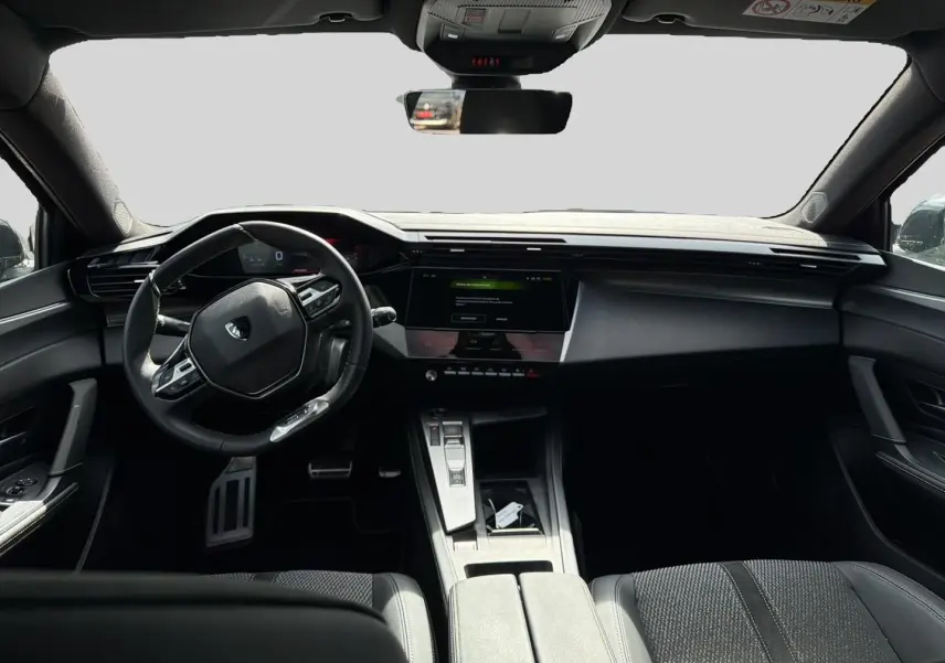 Vue intérieure avant de la Peugeot 308 noire 2025, avec tableau de bord numérique et volant multifonction compact.