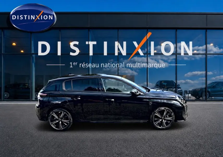 Profil côté gauche d'une Peugeot 308 noire 1.2 hybrid 145 GT e-DCS6 devant une vitrine Distinxion.