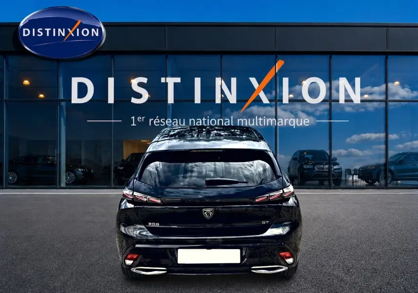 Vue arrière d'une Peugeot 308 noire 2025 GT avec feux LED et double sortie d'échappement chromée, devant une vitrine Distinxion.
