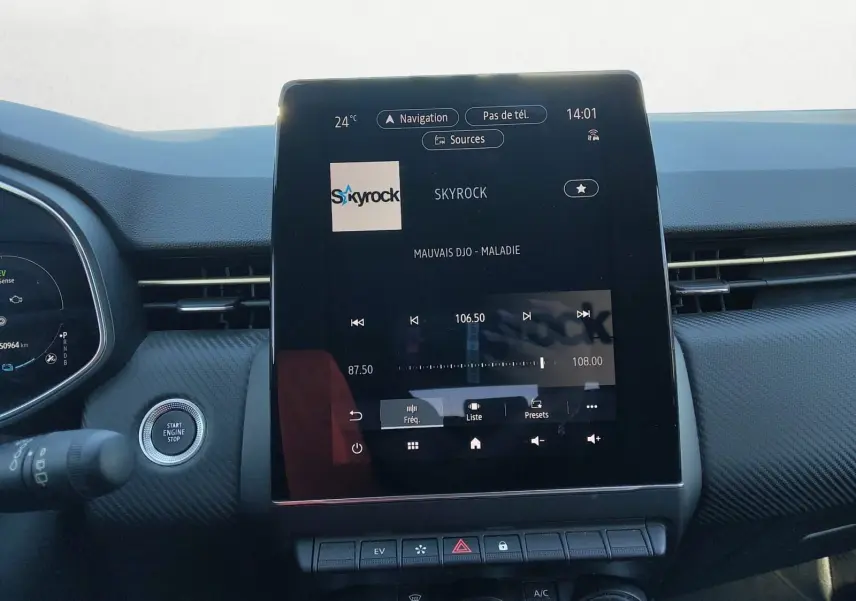Vue intérieure centrée sur l’écran tactile du tableau de bord de la Renault Clio V gris foncé, affichant la radio Skyrock.