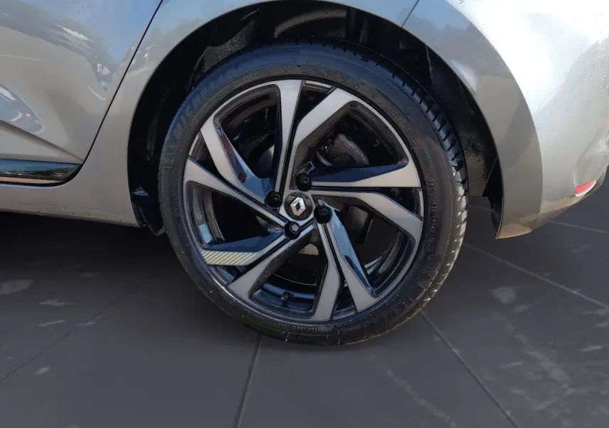 Gros plan sur la roue arrière droite d’une Renault Clio V gris foncé métal avec jante alliage noire et argentée.