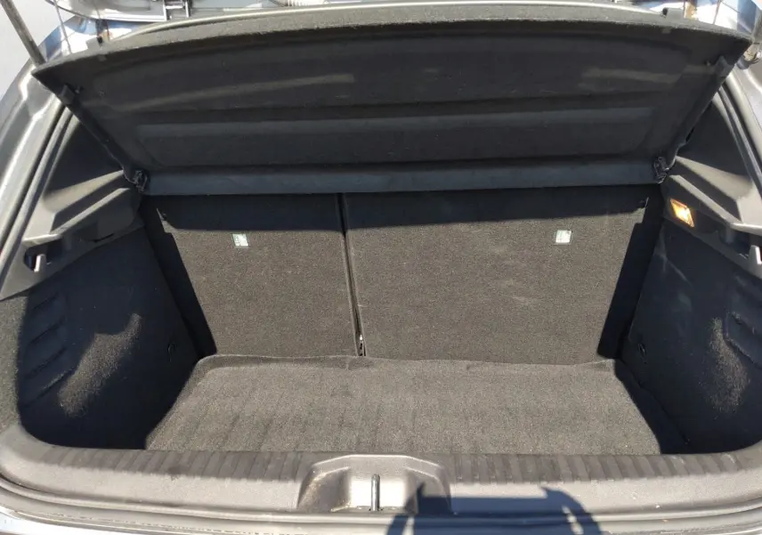 Coffre ouvert vu de face d'une Renault Clio V E-Tech Full Hybrid gris foncé métal, intérieur noir et tapis de coffre propre.