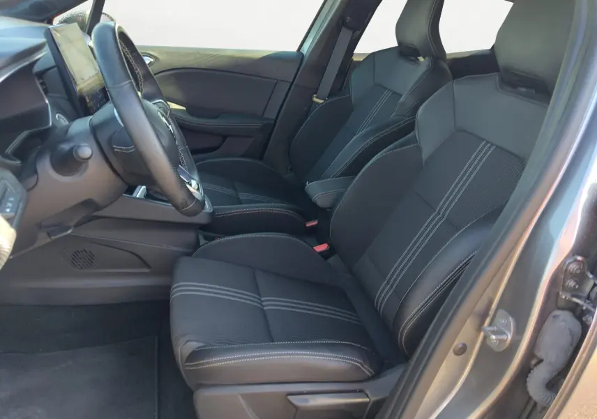 Vue intérieure côté conducteur de la Renault Clio V E-Tech hybride 2023, sièges noirs avec surpiqûres blanches.