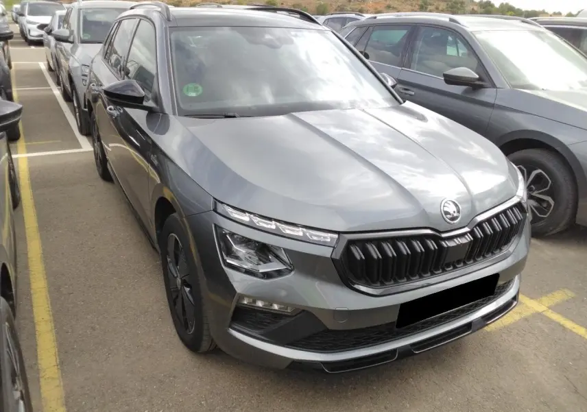SKODA KAMIQ TSI 116 DSG7 Monte-Carlo gris graphite vu en 3/4 avant avec calandre noire et jantes spécifiques.