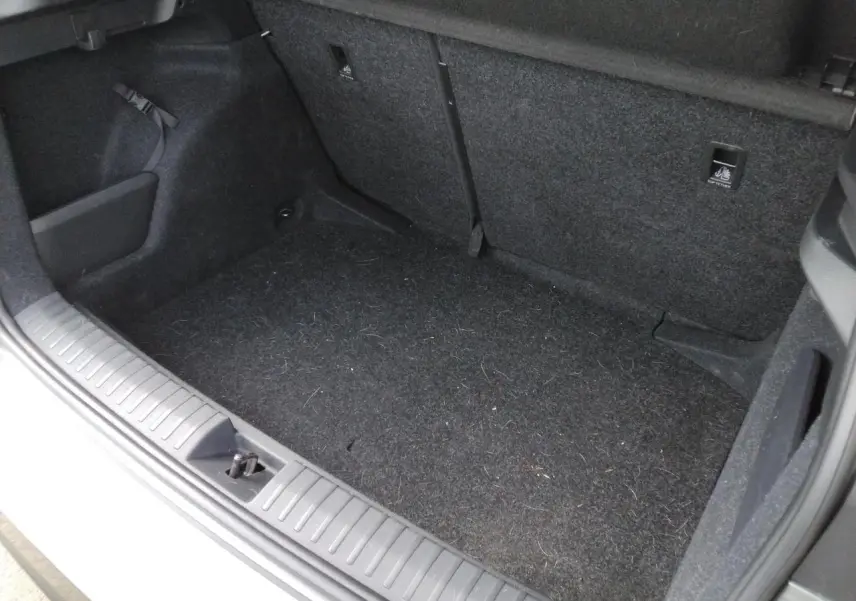 Vue intérieure du coffre ouvert du Skoda Kamiq TSI 116 DSG7 Monte-Carlo, moquette noire et garnitures sombres visibles.
