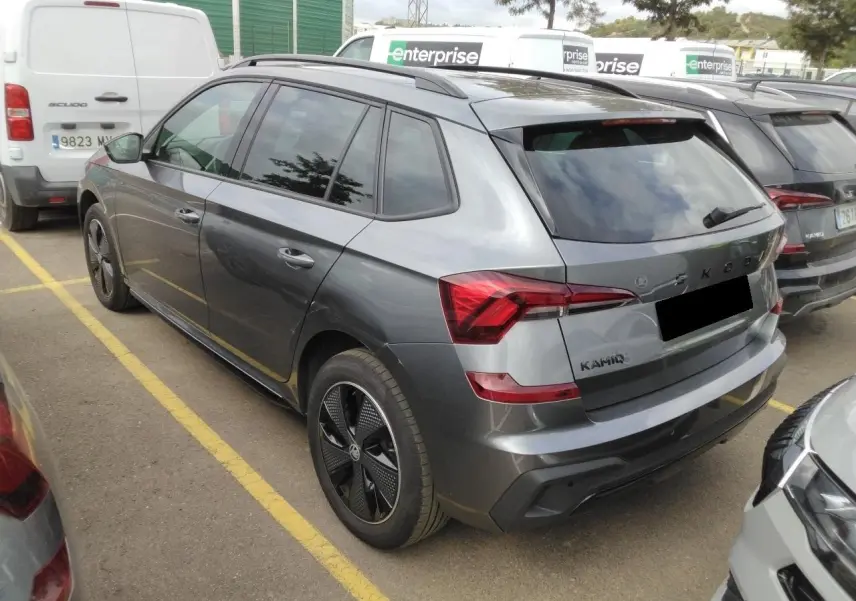 Vue 3/4 arrière droite d'un Skoda Kamiq gris graphite avec jantes alliage noires et toit panoramique.