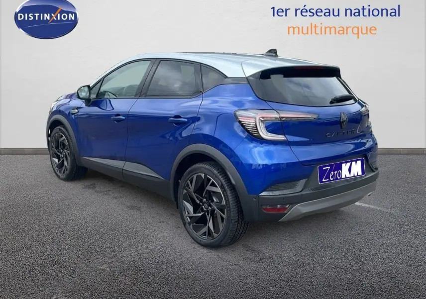 Renault Captur E-Tech hybride bleu Iron Metal avec toit gris, vue 3/4 arrière côté gauche, jantes noires distinctives.