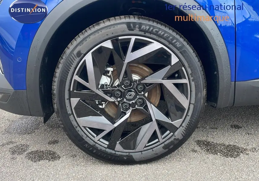 Gros plan sur la roue avant droite du Renault Captur bleu Iron Metal avec jante noire et argentée au design géométrique.