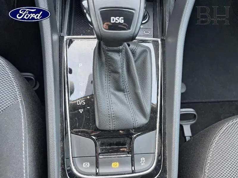 Gros plan sur levier de vitesses DSG noir et console centrale entre sièges tissu gris, intérieur d'un véhicule Ford.