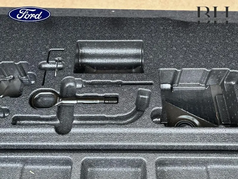 Gros plan sur le rangement d'outils dans le coffre d'un Skoda Kodiaq noir Magic Nacré, hayon ouvert.