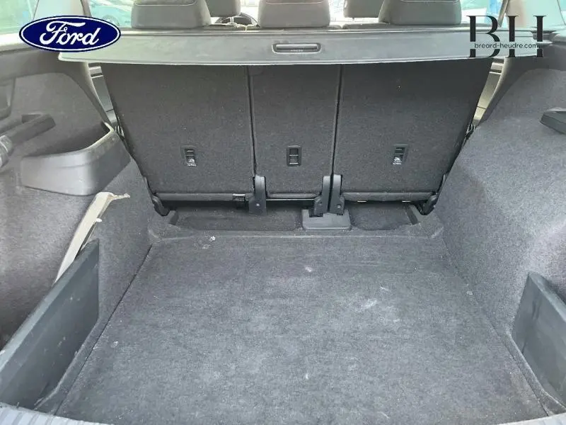 Coffre ouvert d'un Skoda Kodiaq noir Magic Nacré, vue arrière montrant la banquette arrière et l'espace de chargement.