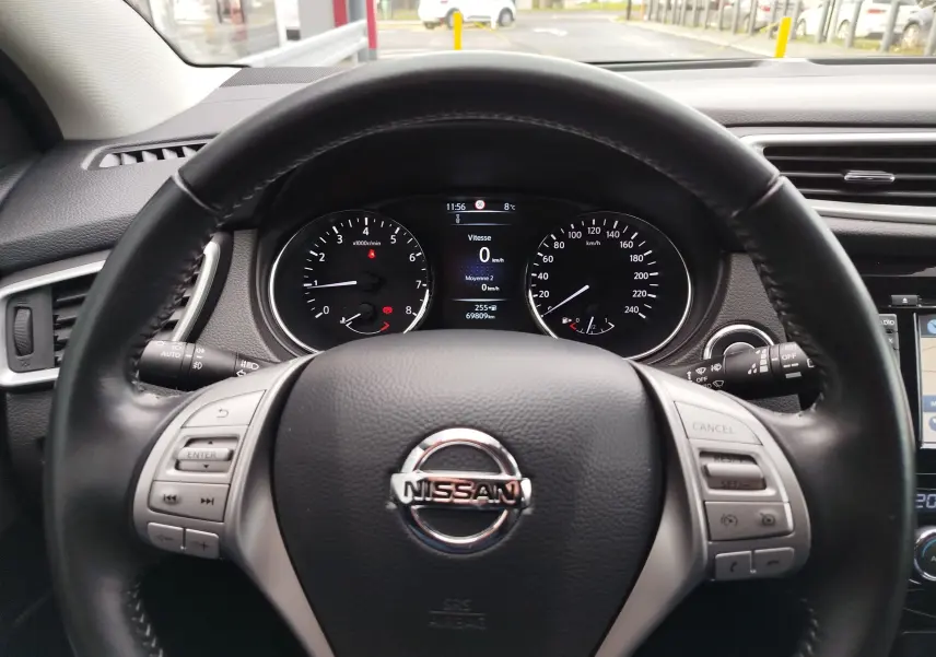 Brochure montrant un Nissan Qashqai bleu en ville de face, avec manuels gris Nissan en arrière-plan.