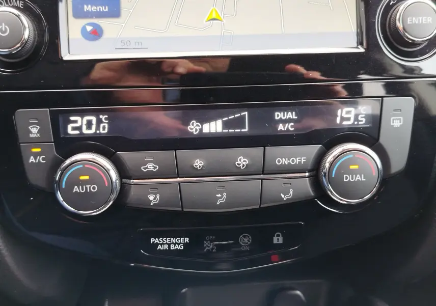 Vue depuis l'intérieur sur le rétroviseur central montrant l'arrière du Nissan Qashqai bronze Ultime et des véhicules en stationnement.