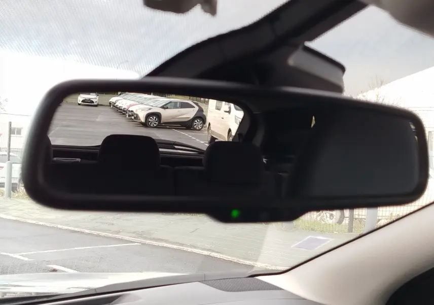 Vue 3/4 arrière droite d'un Nissan Qashqai bronze Ultime avec jantes alliage et vitres teintées, stationné devant un showroom.